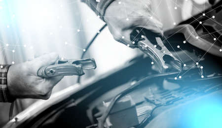 Hands of car mechanic using cables to start a car engine; light effectの写真素材