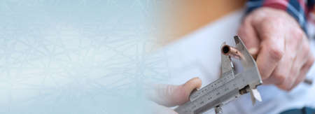 Plumber measuring a copper tube with a caliper; panoramic banner