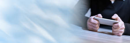Male hand using mobile phone; panoramic banner
