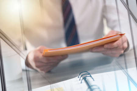 Businessman holding folder with paper documents; multiple exposureの写真素材