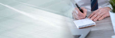 Male hands with pen writing on notepad; panoramic banner