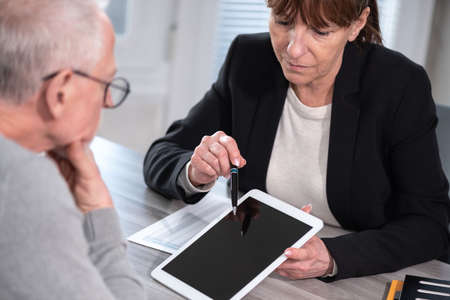 Female financial adviser giving information on digital tablet to her clientの写真素材