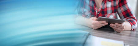 Female hands holding and using digital tablet; panoramic banner