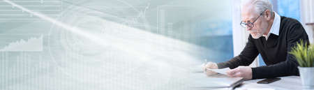 Senior businessman working on document at office; panoramic banner