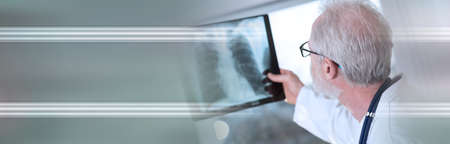 Doctor looking at x-ray report; panoramic bannerの写真素材