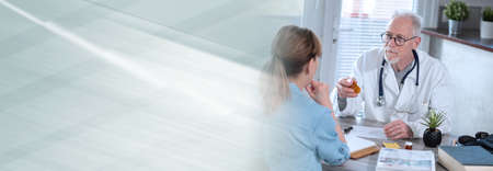 Senior doctor having a discussion with his female patient in medical office; panoramic banner