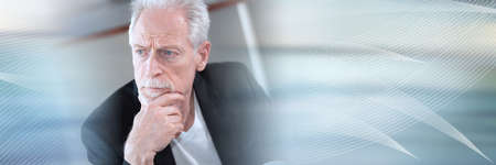 Portrait of thoughtful senior businessman with hand on chin; panoramic bannerの写真素材