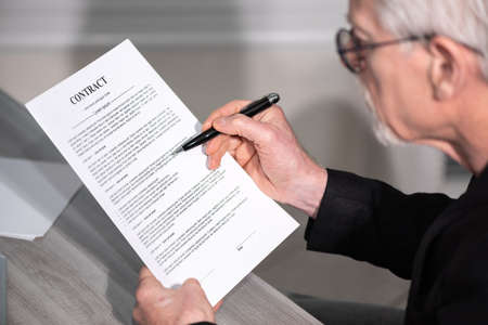 Senior man checking content of a contract