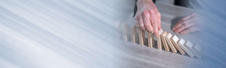 Male hand stopping domino effect. concept of business control; panoramic banner