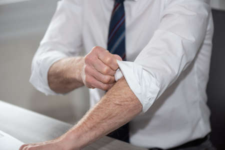 Businessman rolling up his sleeves; concept of motivation
