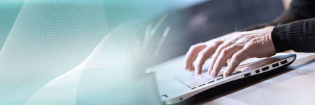 Male hands typing on laptop keyboard; panoramic banner