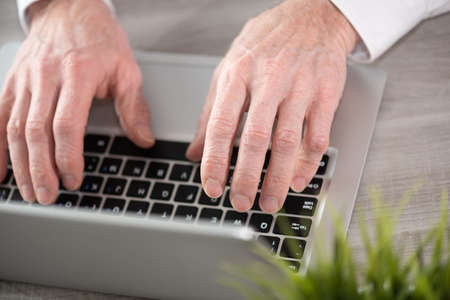 Male hands working on laptop in officeの写真素材