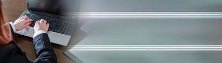 Businesswoman typing on a laptop at office; panoramic banner