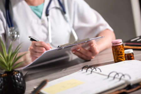 Female doctor taking notes on clipboard at workplaceの写真素材