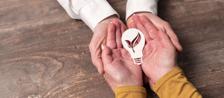 Concept of green energy with paper light bulb in hands
