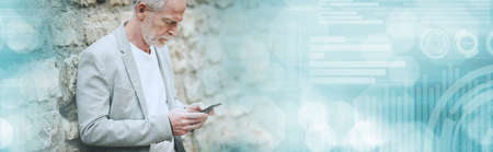 Mature man using his mobile phone outdoors; panoramic banner