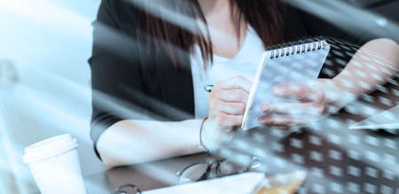 Young woman taking notes on notepad; light effectの写真素材