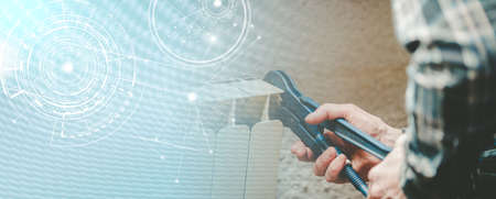 Repairman working on radiator with wrench; panoramic banner
