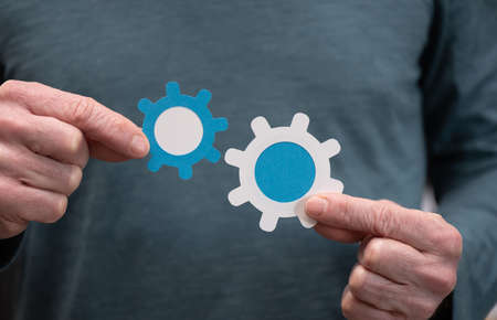 Man holding two paper cogwheels; Concept of business cooperation