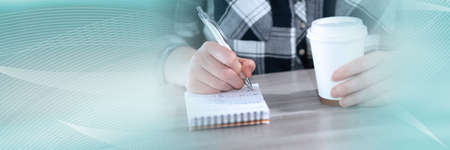 Female hands taking notes on notepad; panoramic banner