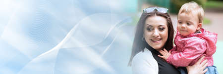 Portrait of cute baby girl held by her mother, outside; panoramic bannerの写真素材