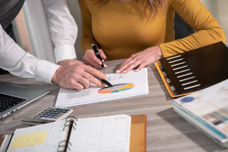 Coworkers working on financial statistics in officeの写真素材