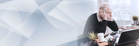 Overworked businessman sitting at a messy desk in office; panoramic bannerの写真素材