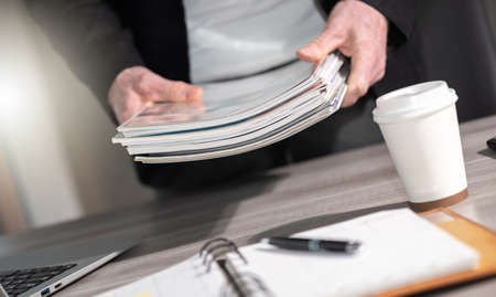 Male hands holding a stack of magazines
