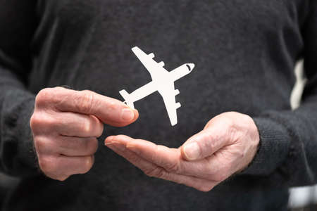 Man holding a paper airplane; Concept of flight insuranceの写真素材