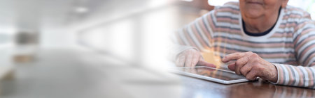 Elderly woman using a digital tablet; panoramic bannerの写真素材