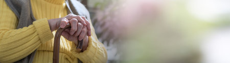 Old woman sitting with her hands on a cane; panoramic bannerの写真素材