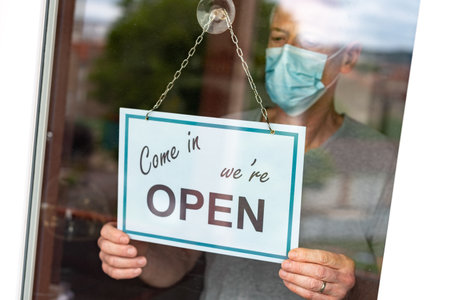 Store owner hanging come in we're open sign on window