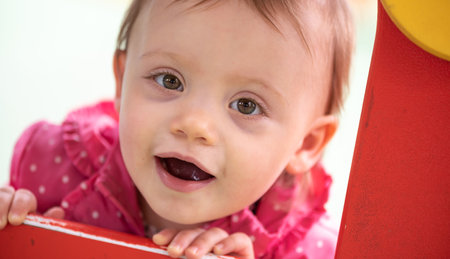 Cute baby girl having fun on a playground and looking at the camera