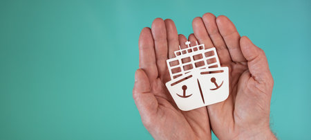 Concept of marine insurance with paper ship in hands on turquoise color backgroundの写真素材