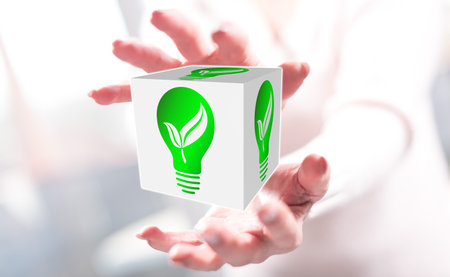 Green energy concept between hands of a woman in backgroundの写真素材