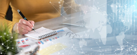 Businesswoman taking notes while using laptop; panoramic banner