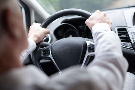 Man driving with his two hands on steering wheel