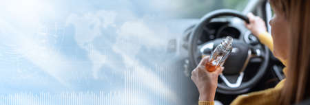 Woman drinking alcohol while driving; panoramic banner