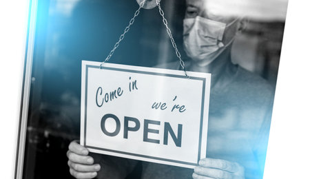 Store owner hanging come in we're open sign on window; light effect