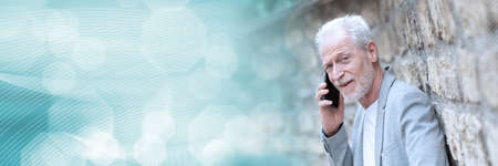 Mature man using his mobile phone outdoors; panoramic bannerの写真素材