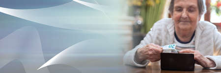 Elderly woman taking out a banknote from her wallet; panoramic banner