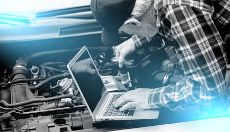 Car mechanic using laptop for checking car engine; light effect