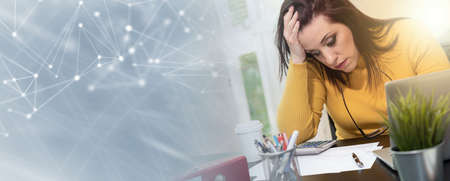Desperate young businesswoman with hand on forehead sitting at desk; panoramic banner