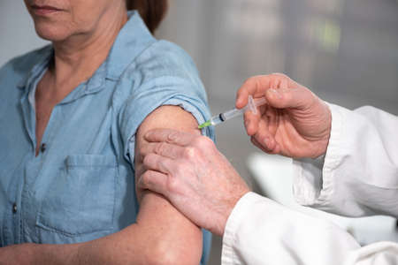 Doctor injecting vaccine to female patient