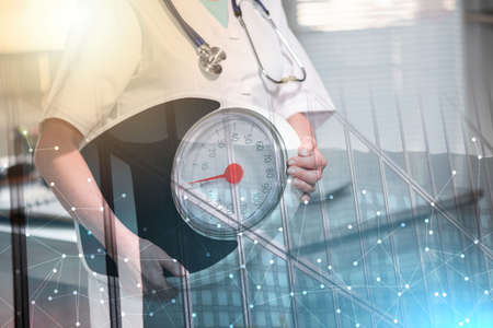 Female doctor holding a weight scale; concept of healthy eating; multiple exposureの写真素材