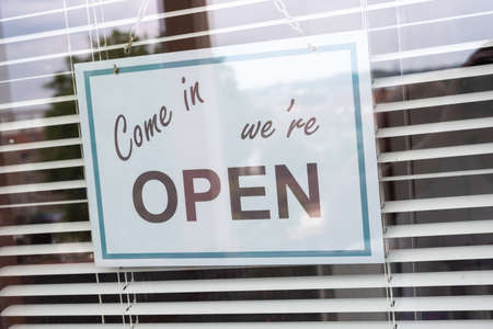 Come in we're open sign hanging behind a store windowの写真素材