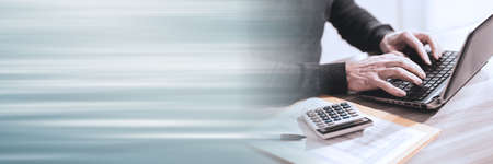 Male accountant working on laptop; panoramic banner