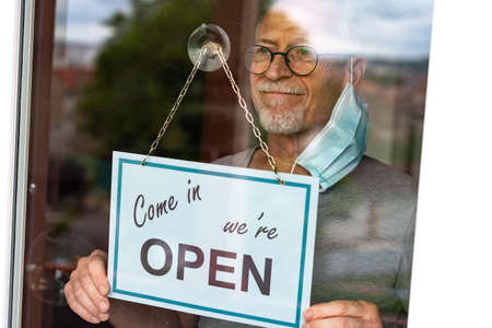 Store owner hanging come in we're open sign on windowの写真素材