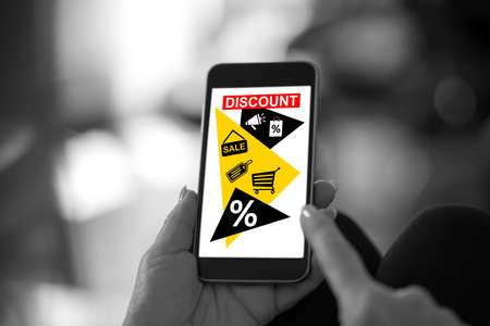 Hand holding a smartphone with discount conceptの写真素材