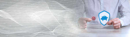 Man holding a virus and shield with a piggy bank; concept of saving protection during covid-19 outbreak; panoramic bannerの写真素材